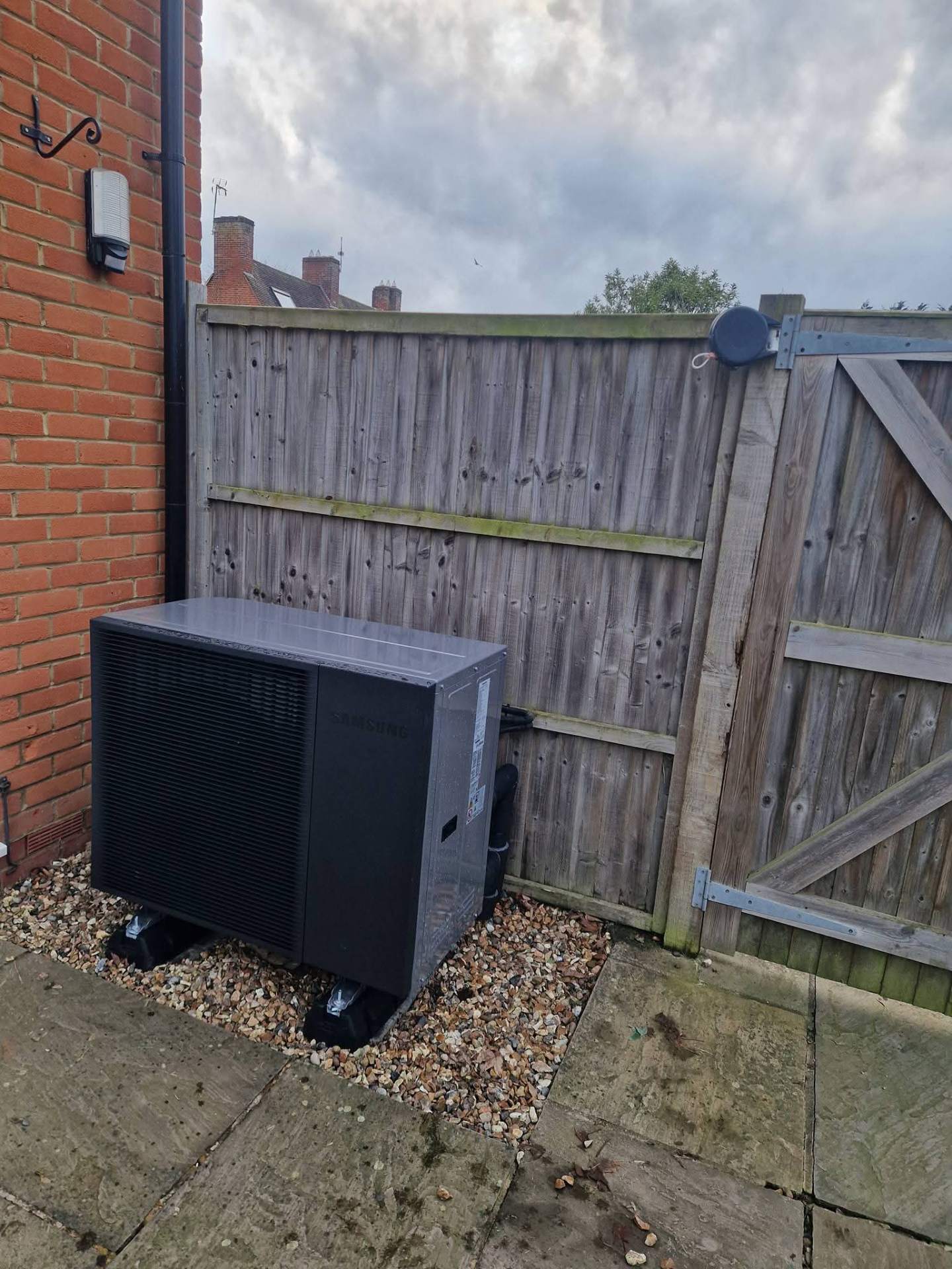 Heat pump outdoor unit installed in side passage with correct clearance distances maintained