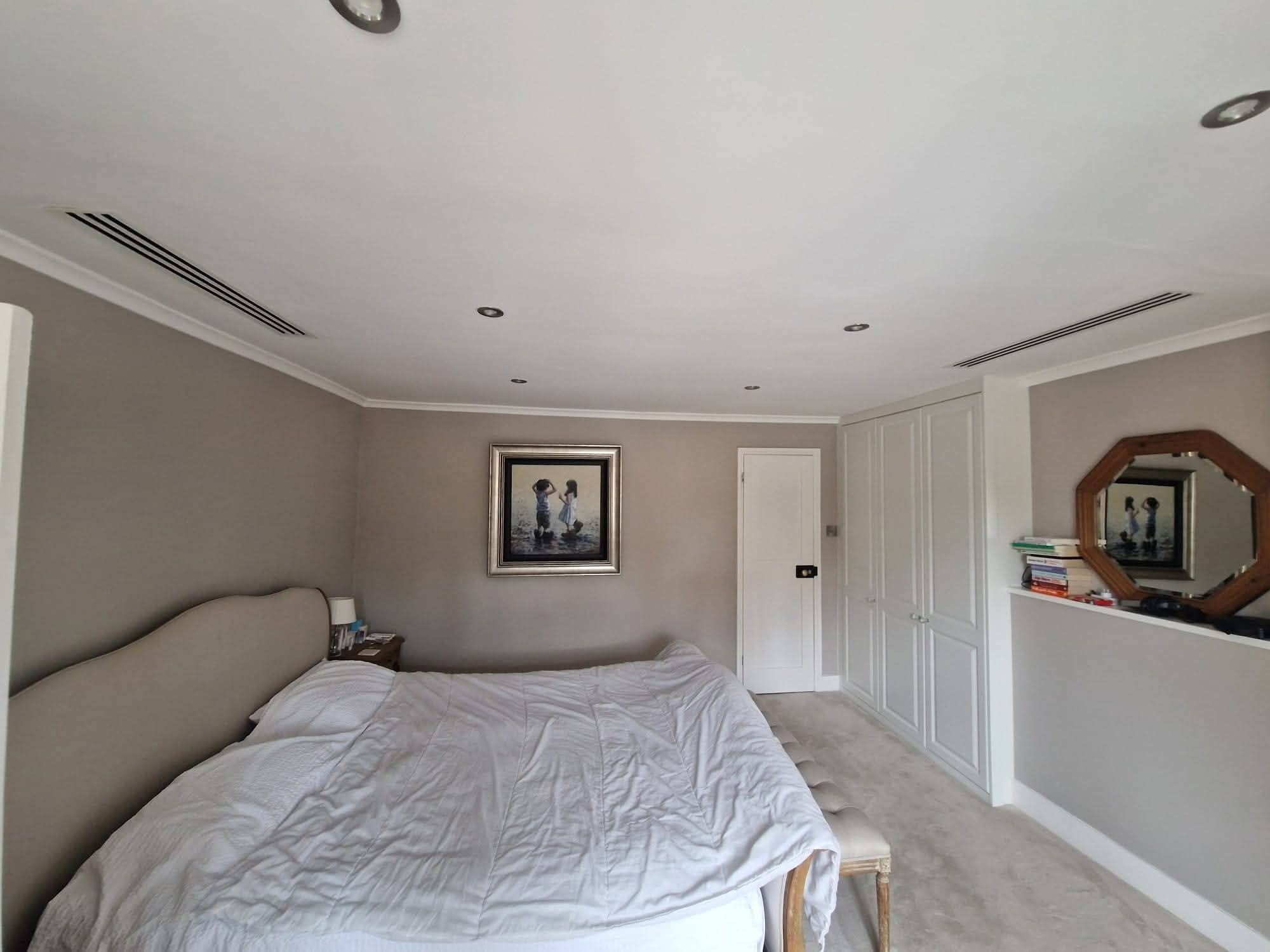 Split air conditioning outdoor condenser unit mounted on wall brackets at a domestic property